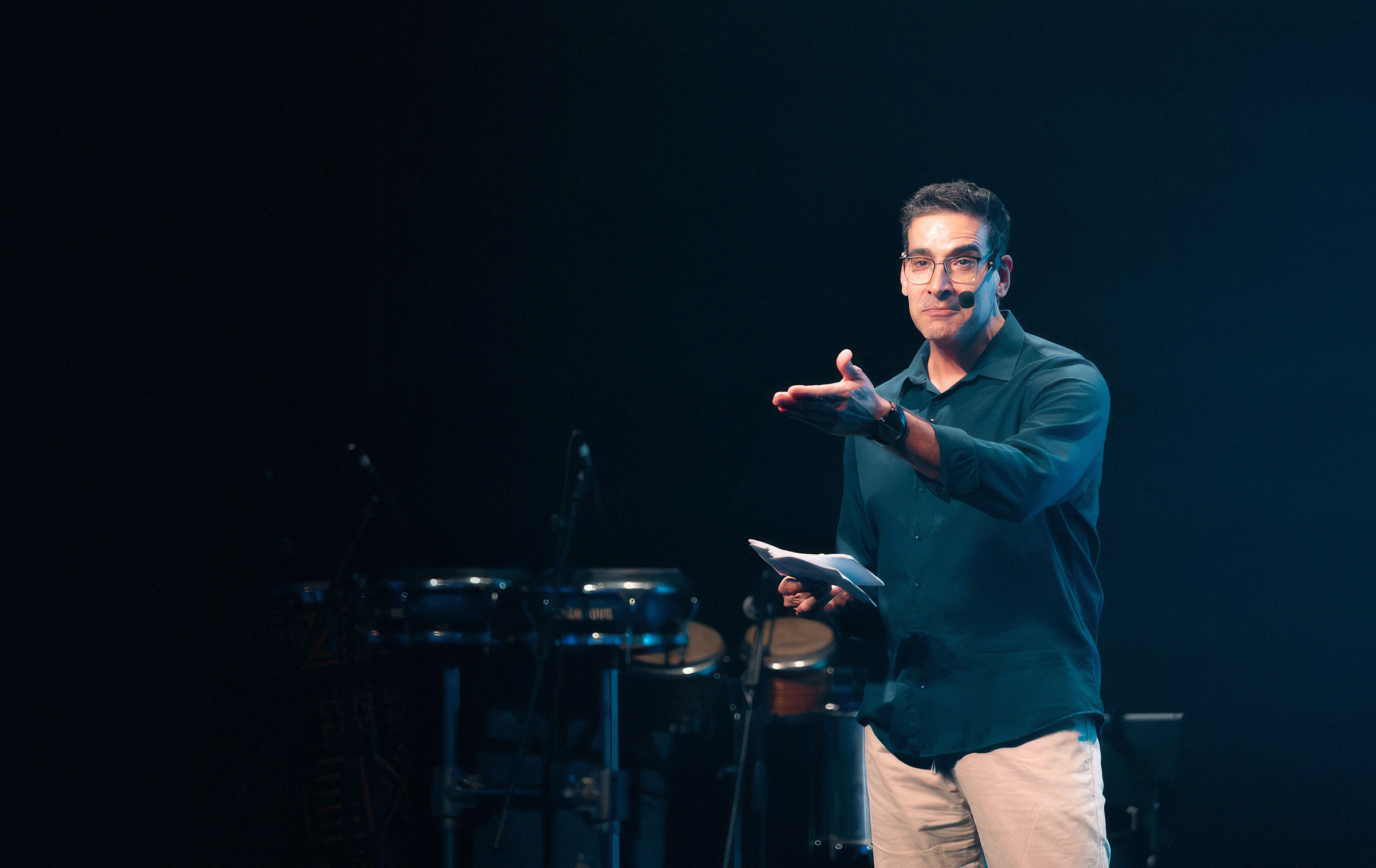 Gabriel Tacco apresentando no palco, com microfone de lapela